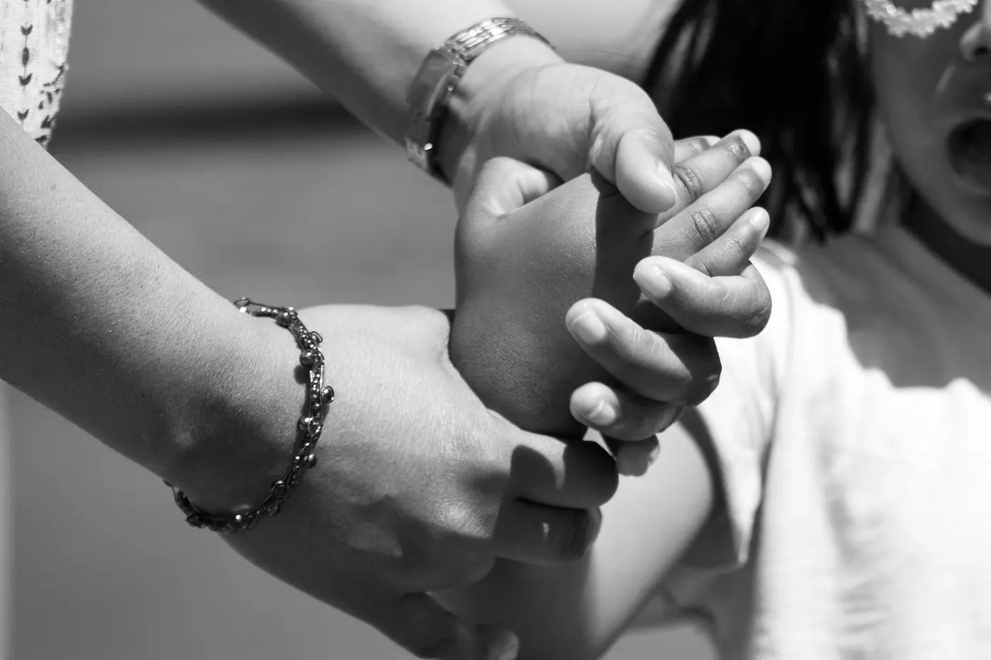Eine Mutter hält die Hand ihres Kindes, beide tragen Armbänder
